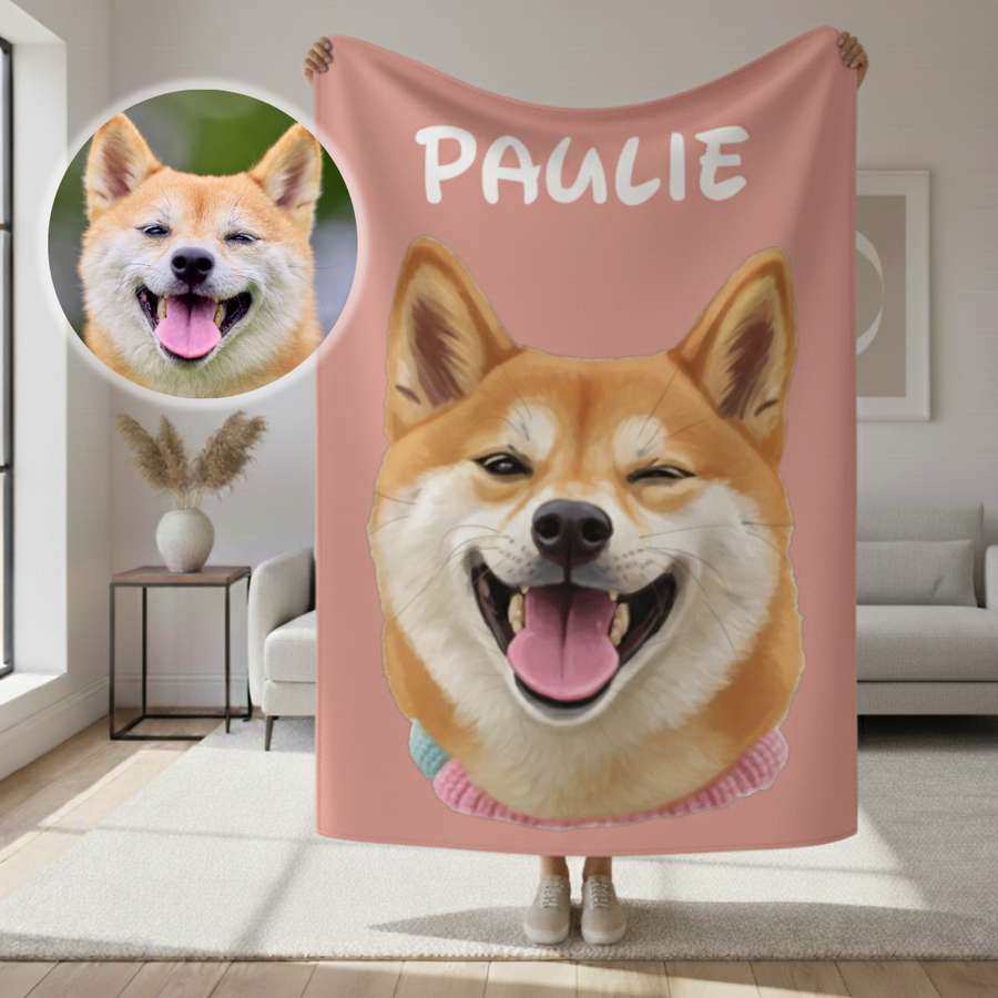Pink sherpa blanket with cartoon-style illustration of a smiling tan and white dog, personalized with sample name "PAULIE" at top, displayed in a living room with inset photo of the reference dog.