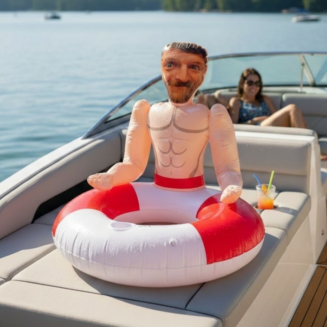 Custom photo ring float with sample face and torso image, red and white inflatable design, displayed on boat deck with water and passengers in background