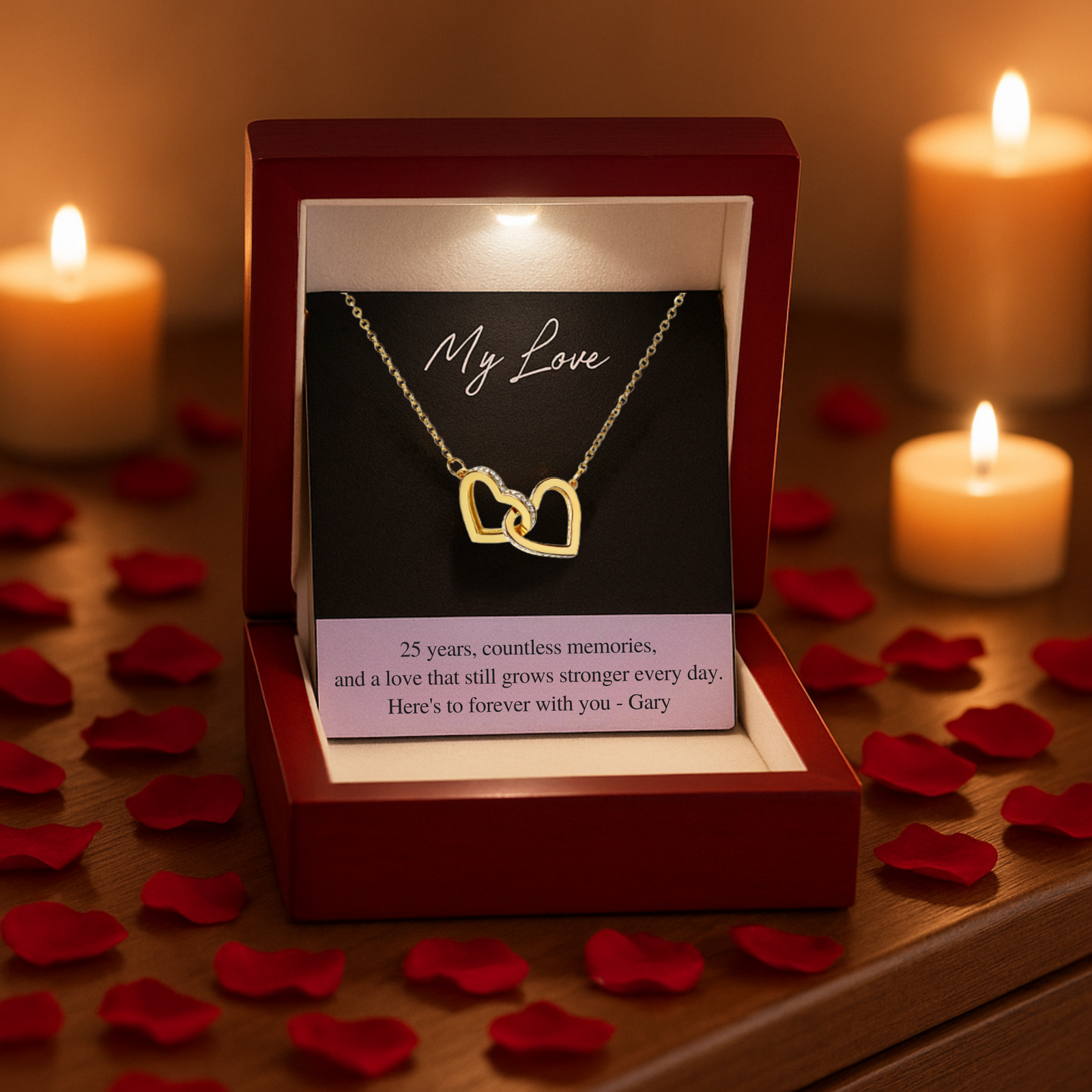 Gold interlocking double heart necklace with cubic zirconia displayed in open mahogany box, showing sample personalized message card reading "25 years, countless memories, and a love that still grows stronger every day. Here's to forever with you - Gary