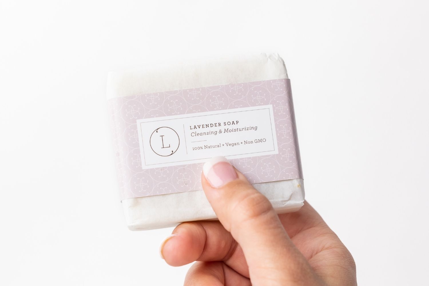 Hand holding a lavender soap bar with a visible brand label on a white background