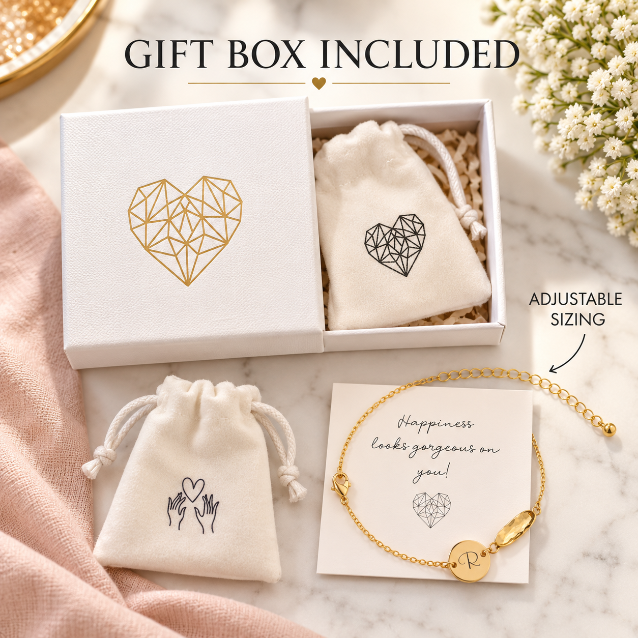 A gold bracelet with a round charm and chain is displayed with its gift box and two small drawstring pouches on a marble surface. Text reads 'GIFT BOX INCLUDED' and 'ADJUSTABLE SIZING.