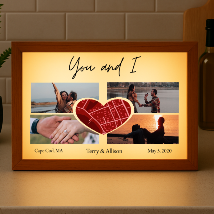 Wooden-framed light box displaying four photos arranged around a red heart map, with "You and I" text at top and sample personalization reading "Cape Cod, MA," "Terry & Allison," and "May 5, 2020