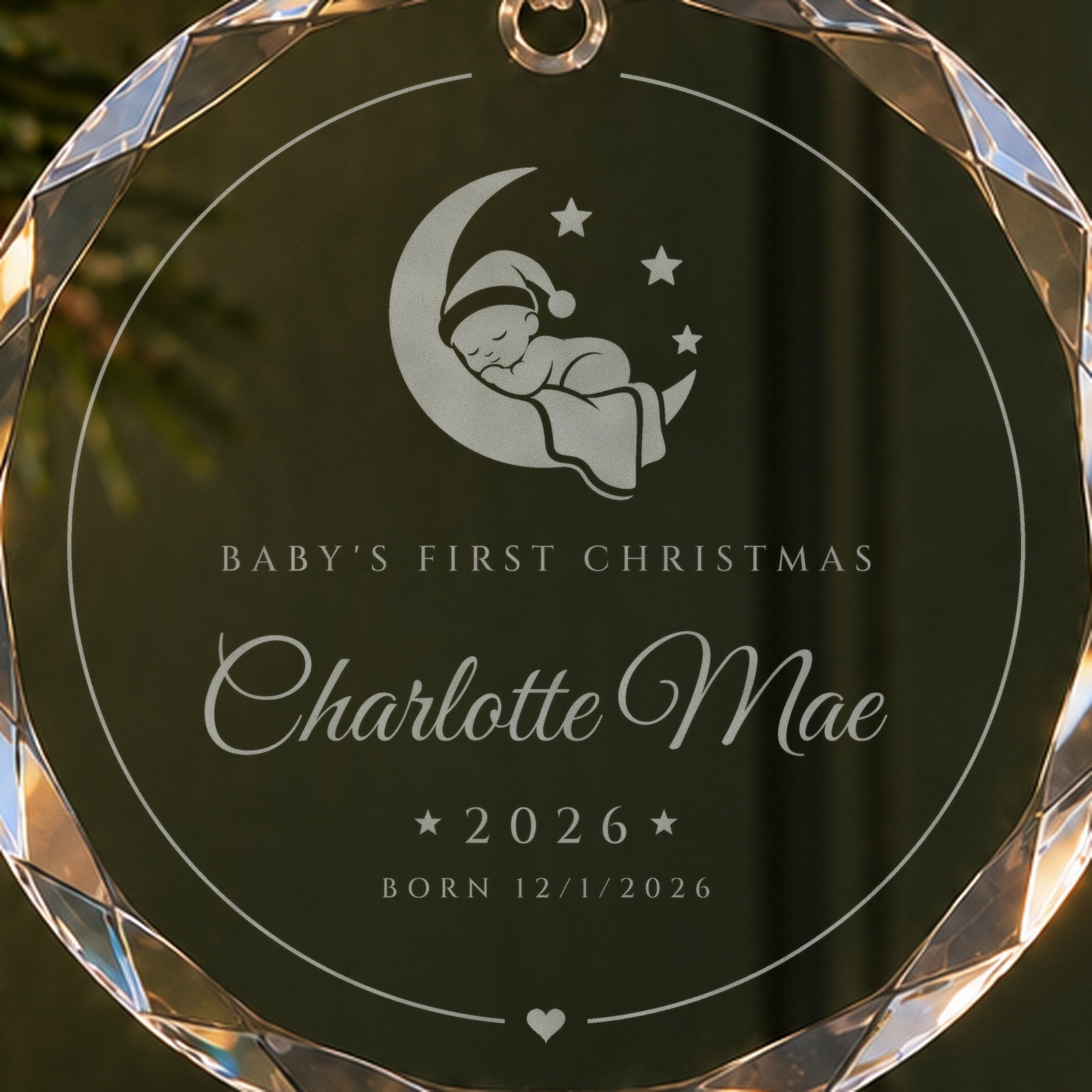 Close-up of the frosted moon baby engraving on the baby's first Christmas ornament, with Charlotte Mae, 2026 and Born 12/1/2026