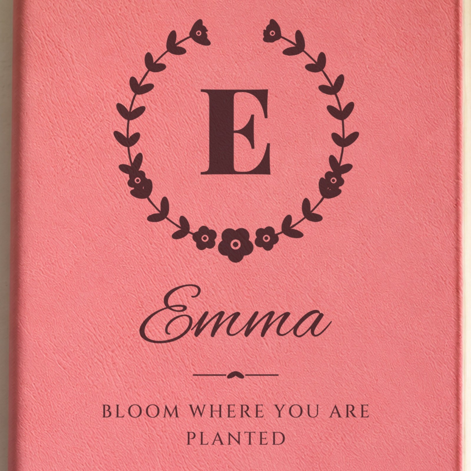 Close-up of the engraving on the wildflower crest journal: the initial E in a floral wreath, Emma in script and Bloom Where You Are Planted