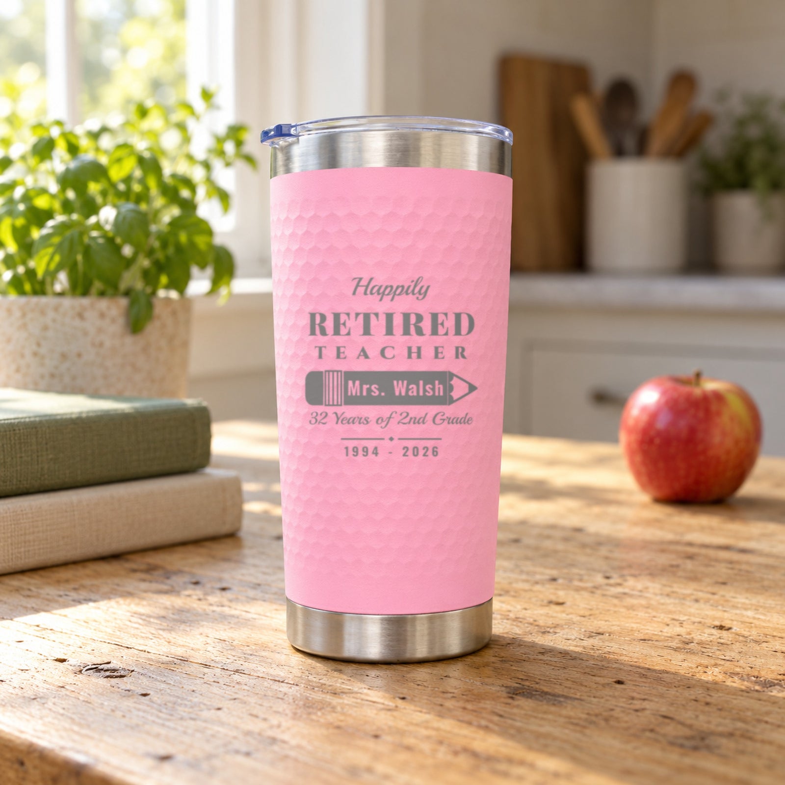 Pink textured tumbler engraved Happily Retired Teacher with Mrs. Walsh on a pencil, a teacher retirement gift on a sunny kitchen table