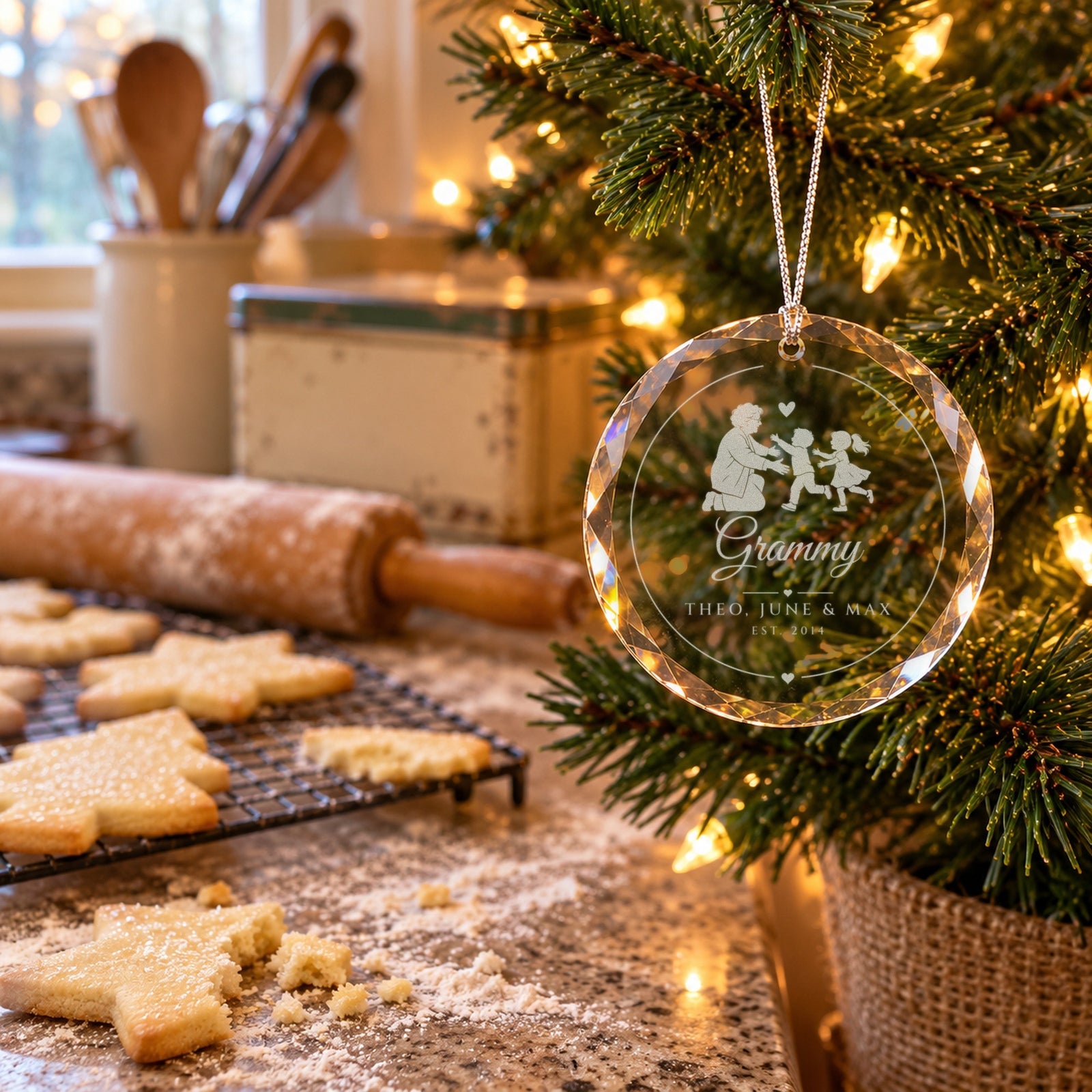 Grandma ornament engraved Grammy, THEO, JUNE & MAX, EST. 2014 on a small tree in grandma's kitchen beside fresh sugar cookies and a floured rolling pin