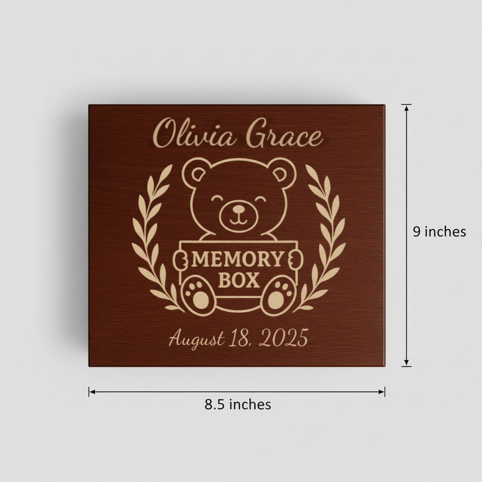 Engraved wood baby keepsake box lid shown with its measurements, 9 inches by 8.5 inches, featuring the teddy bear and laurel wreath design