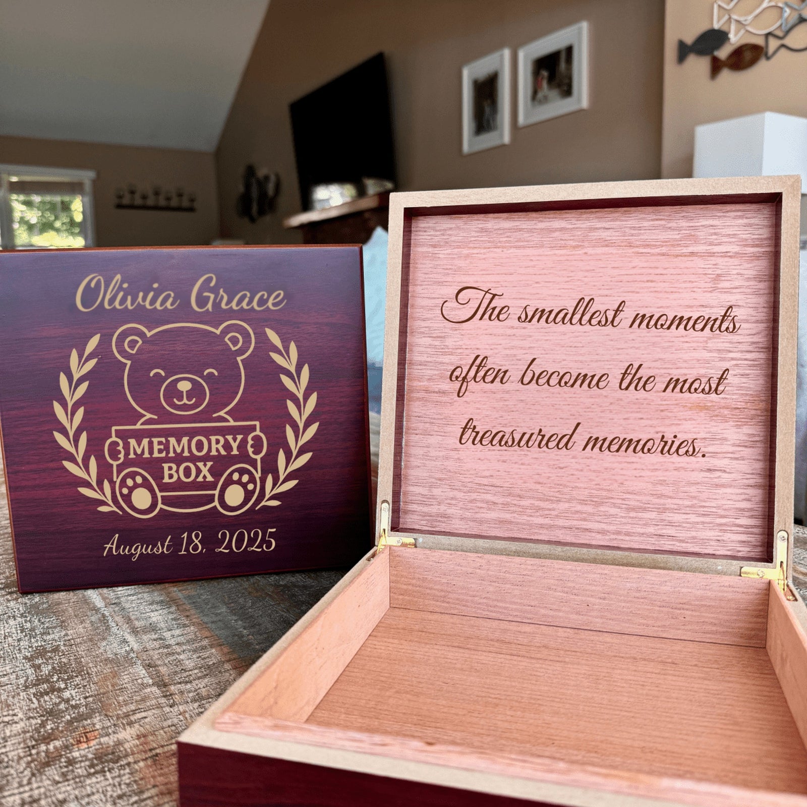 Cherry baby keepsake box on a living room table, lid engraved with the teddy bear design and the open box showing an engraved message inside