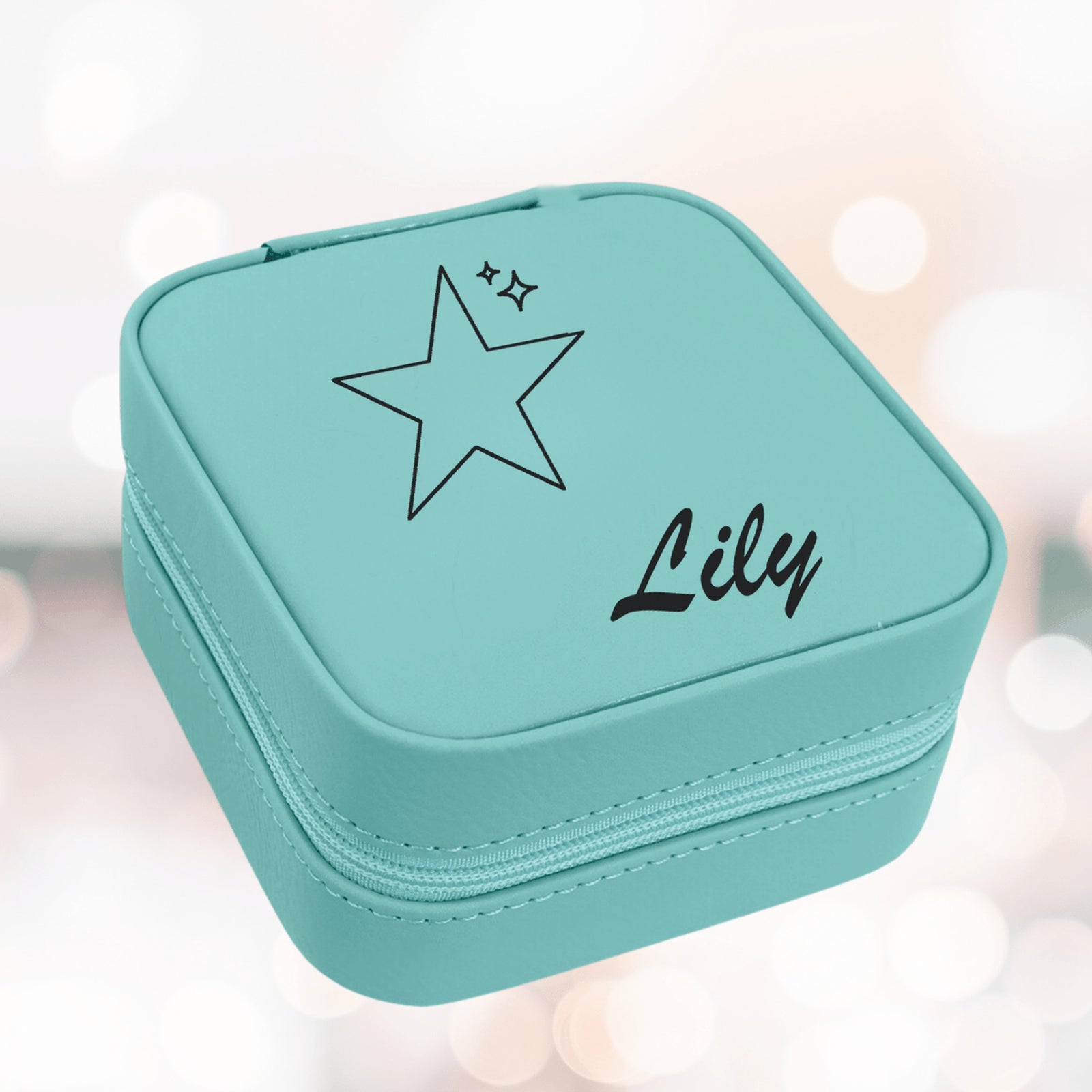 Teal kids jewelry box with a laser engraved star, two small sparkles and the sample name Lily in script on the lid of the zippered case