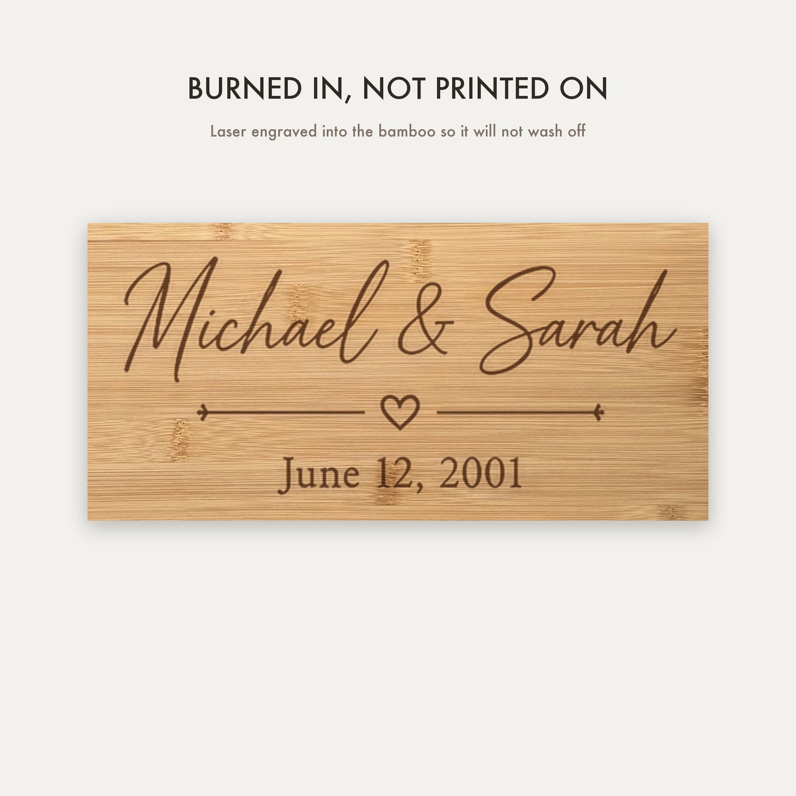 Close view of the laser engraving burned into the bamboo grain showing the couple's names, the heart divider and the wedding date.