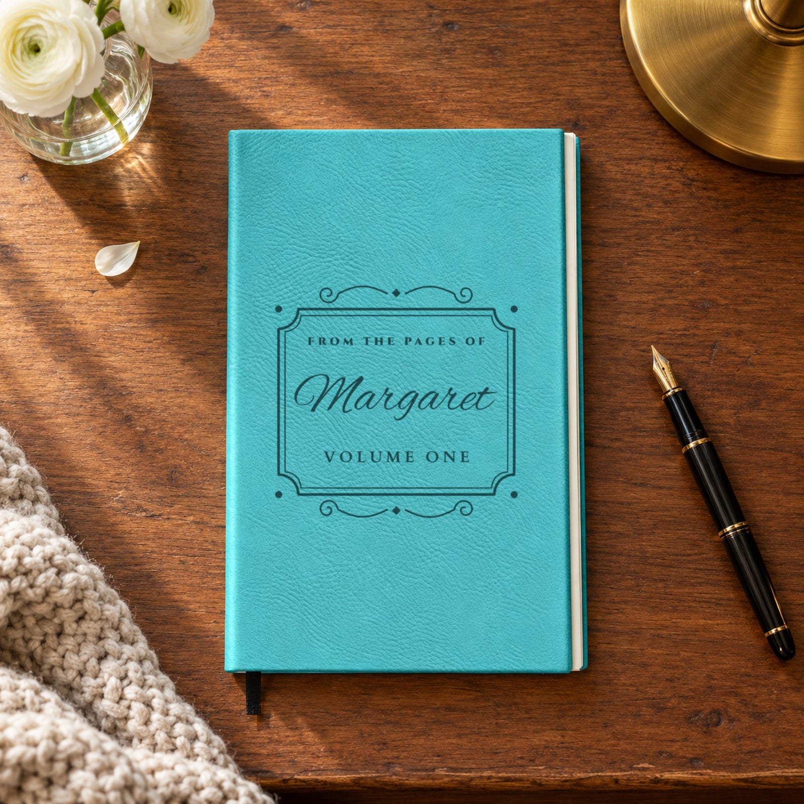 Teal engraved journal on a walnut desk with Margaret in big script and Volume One inside a vintage bookplate frame, a personalized journal gift