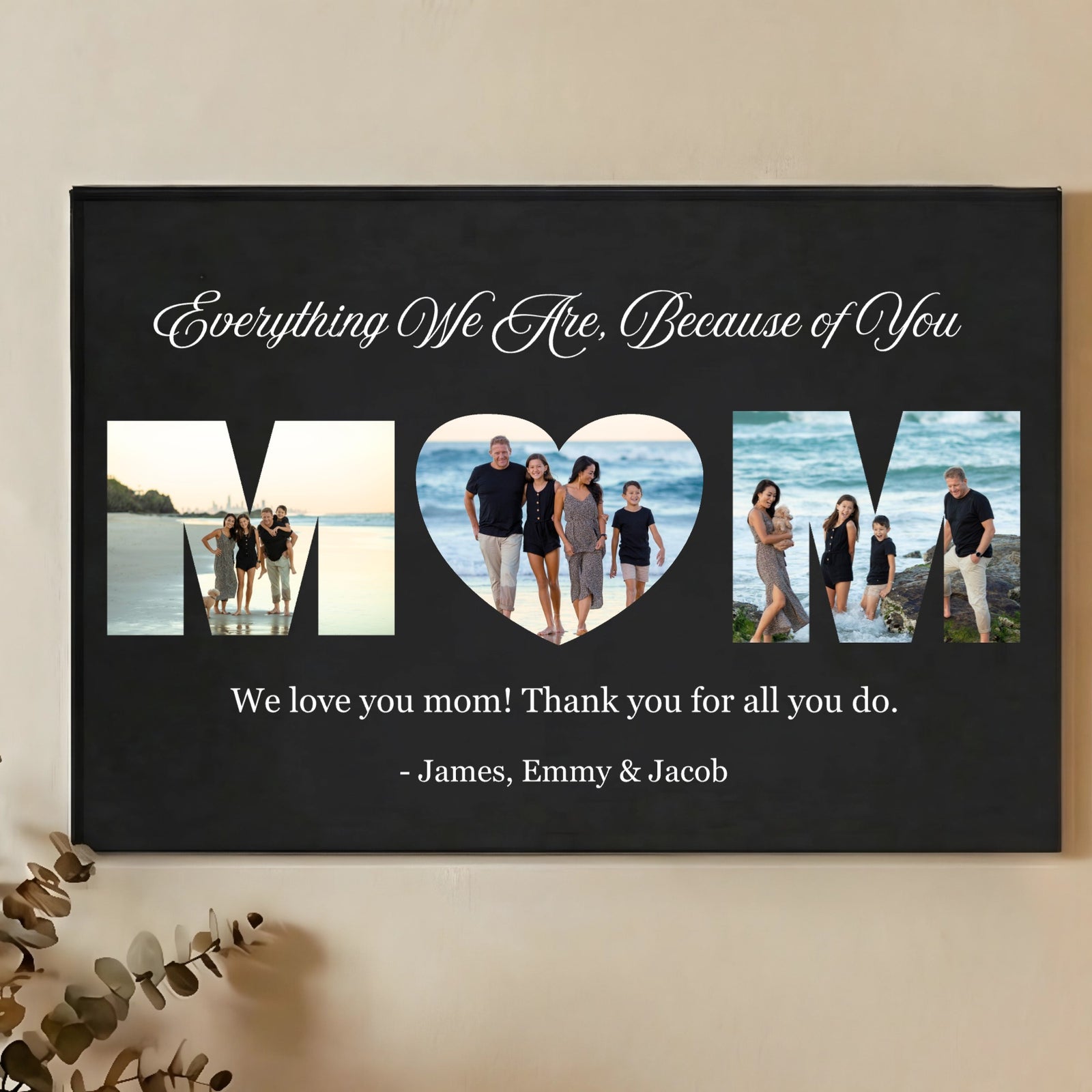 Black wall sign with three photo cutouts spelling MOM, featuring family beach photos, script text reading "Everything We Are, Because of You," and sample names "James, Emmy & Jacob" at bottom