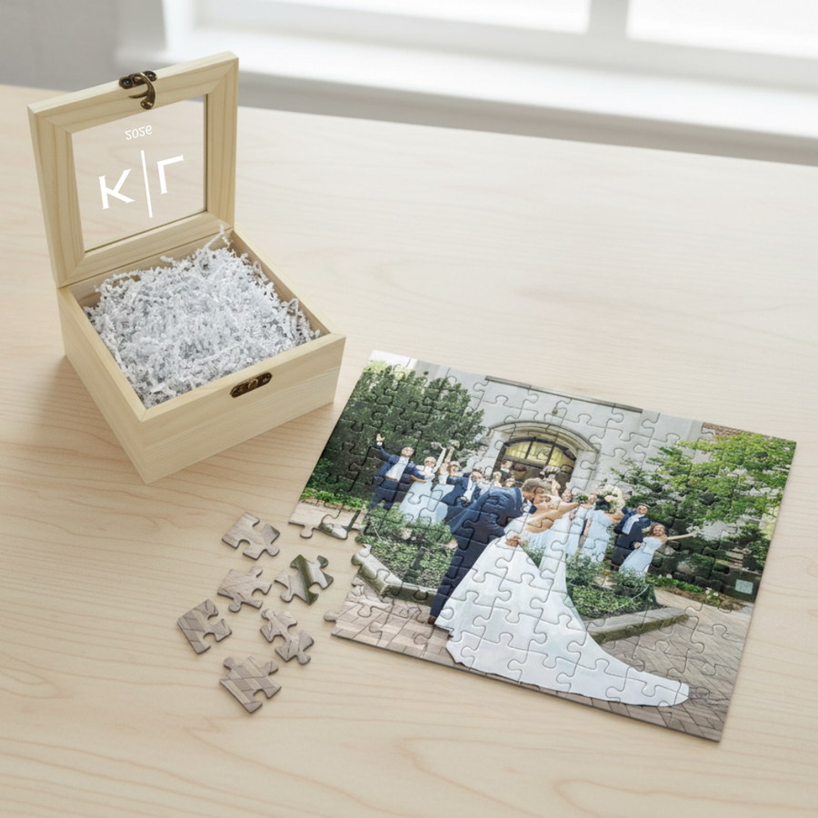 Natural wood keepsake box with glass window engraved with sample initials "K|r" and date, containing 100-piece photo puzzle showing wedding couple photo with scattered pieces displayed below.
