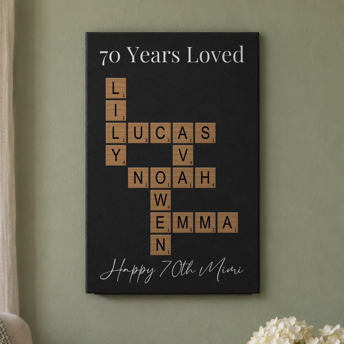 70th birthday gift for women: a 70 Years Loved crossword sign with the grandkids' names and Happy 70th Mimi, hanging on a sage green wall