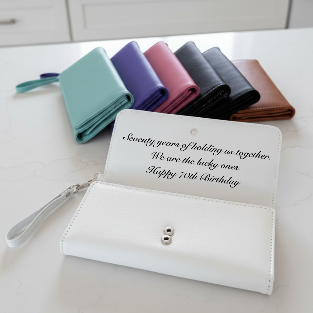 White personalized wristlet engraved inside the flap with a 70th birthday message reading seventy years of holding us together.