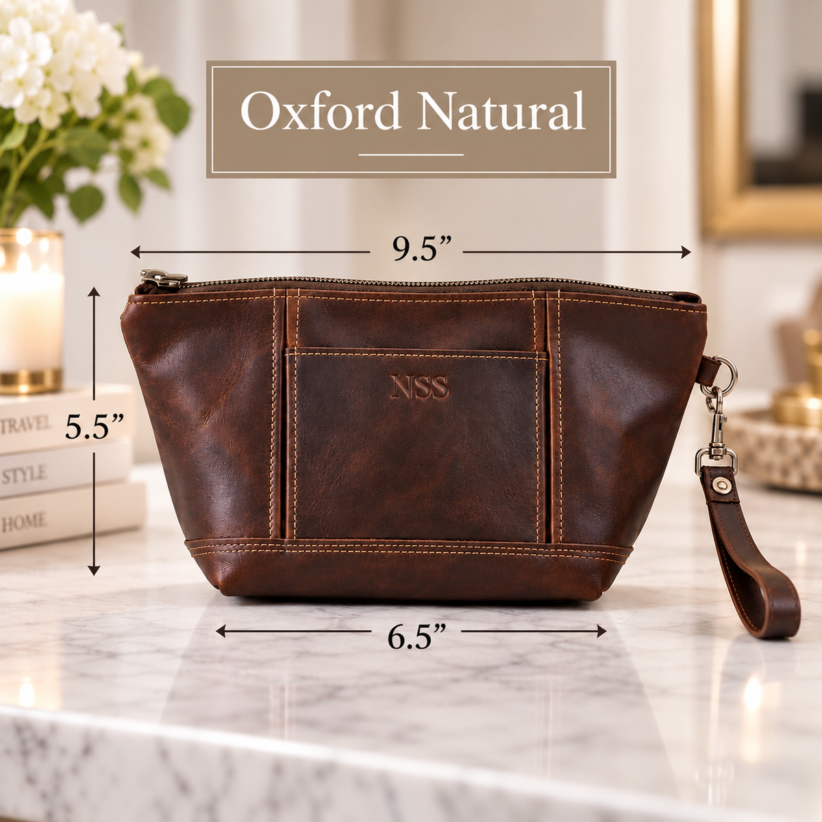 Chocolate brown leather toiletry bag with tan stitching and sample monogram "XXX", dimensions labeled 9.5" W x 5.5" H x 6.5" D, wrist strap attached