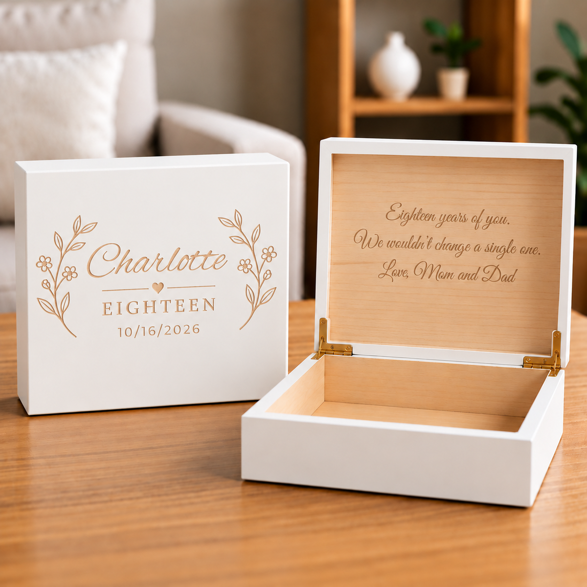 White wooden keepsake box engraved with "Charlotte Eighteen" and date "10/18/2026" flanked by leaf motifs, shown open to reveal wooden interior storage space.