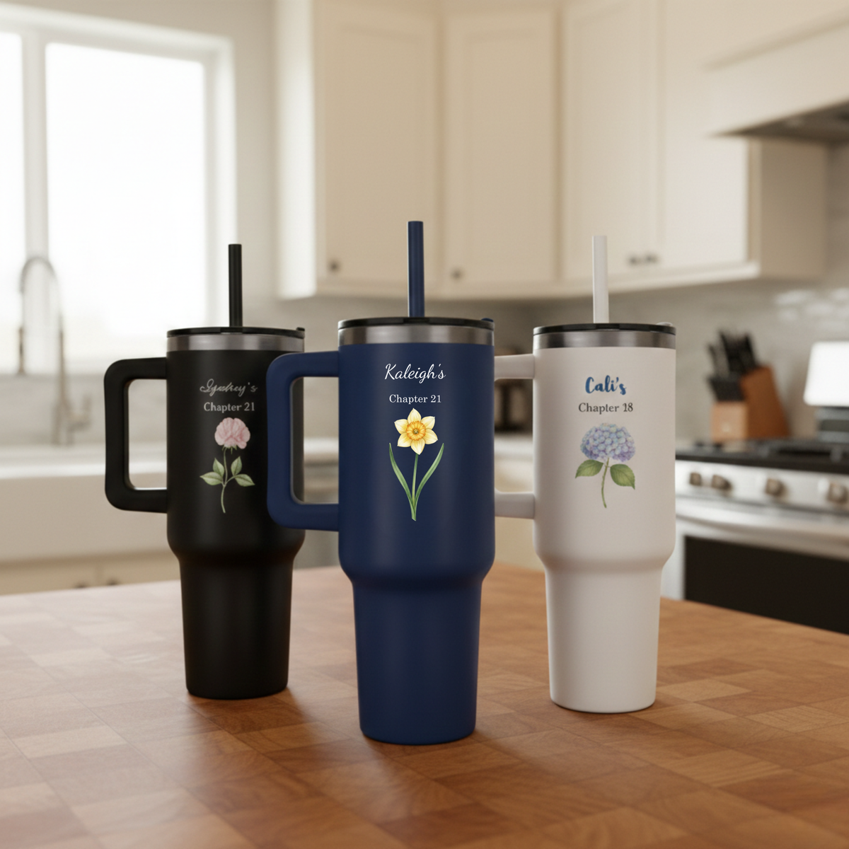 Three personalized tumblers with floral designs on a kitchen counter.