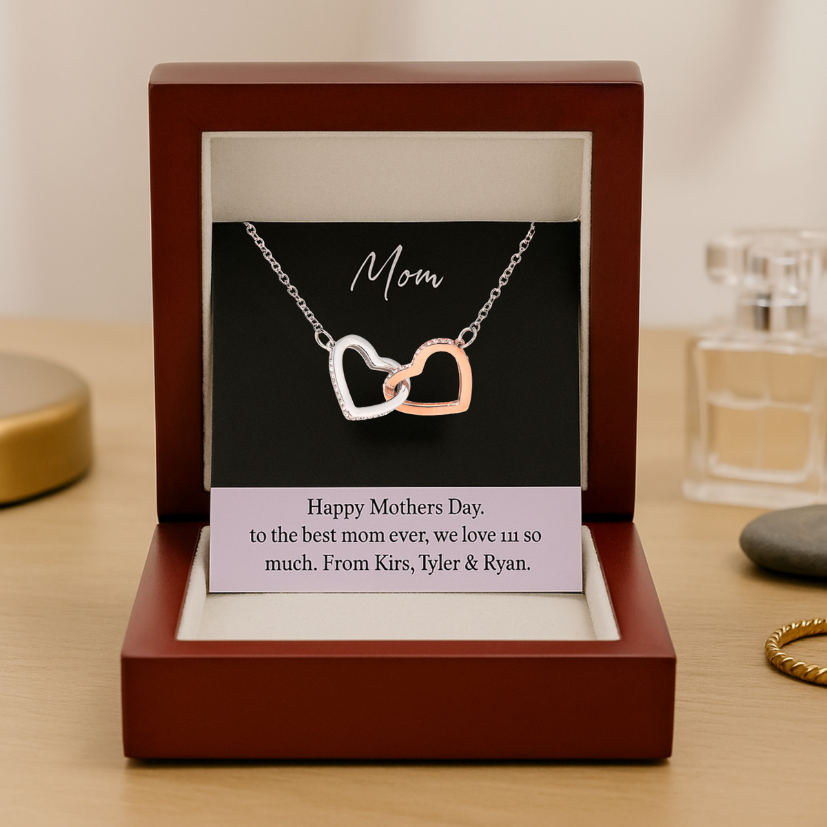Double heart necklace with silver and rose gold interlocking hearts on chain, displayed in mahogany box with personalized message card reading "Happy Mothers Day. to the best mom ever, we love u so much. From Kirs, Tyler &amp; Ryan.