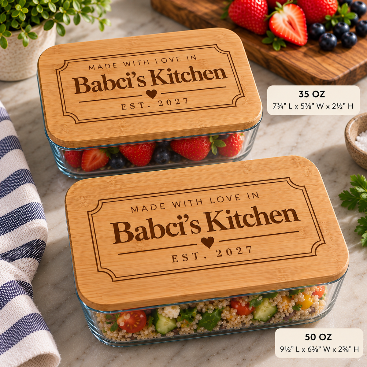 Two rectangular glass food storage containers with bamboo lids are shown on a marble surface. The lids are engraved with the text 'MADE WITH LOVE IN Babci's Kitchen EST.