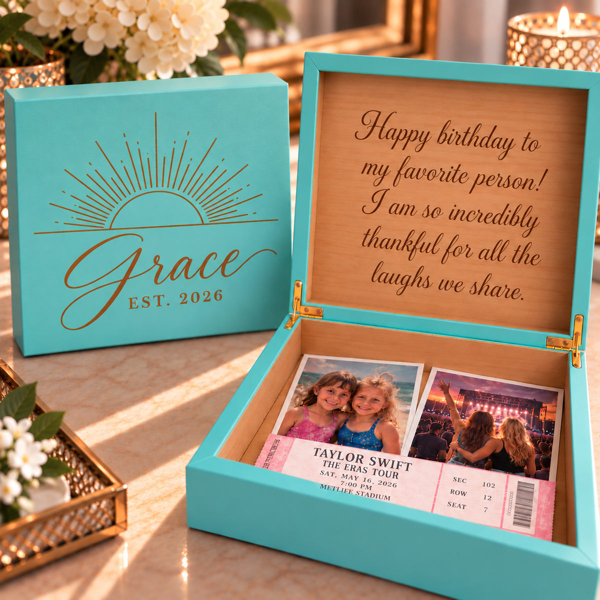 A turquoise keepsake box shown open on a marble surface, with a matching closed box beside it. The inside lid is printed with a birthday message, and the box contains two printed ticket-style photos and a ticket.