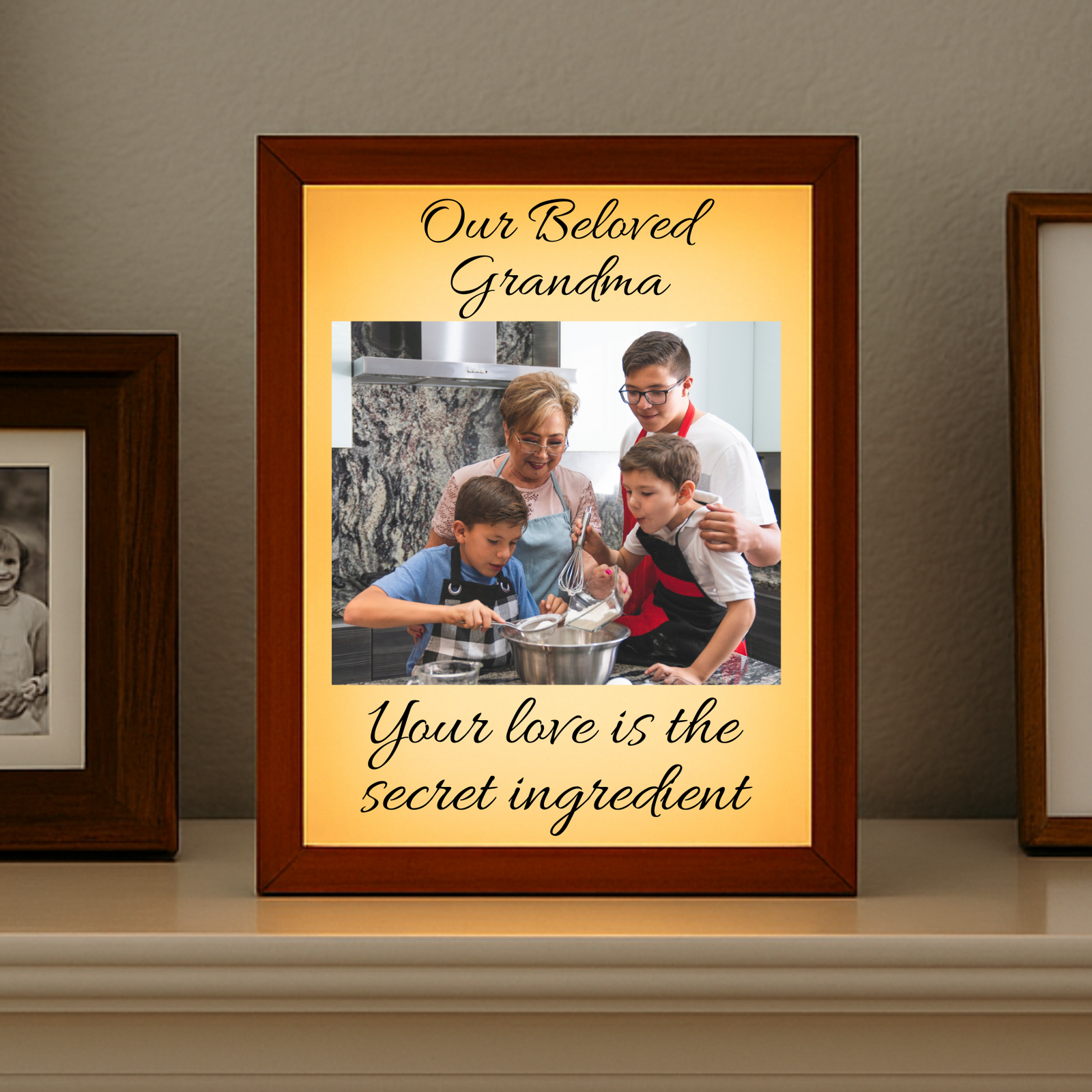 Framed photo of grandkids kissing an grand mother with text 'Mary, Riley & Nonna Best day ever with you!' on a shelf.