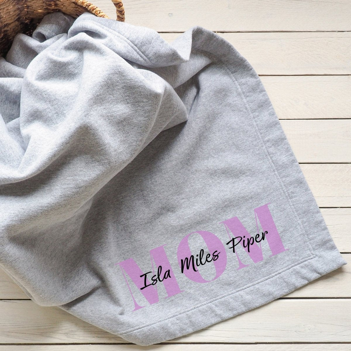 Gray blanket personalized with &quot;Mom&quot; and her children&#39;s names in elegant text.