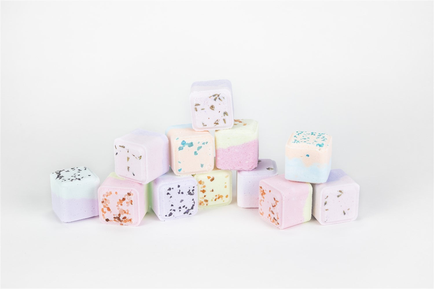 Pastel-colored bath bombs stacked on a white background