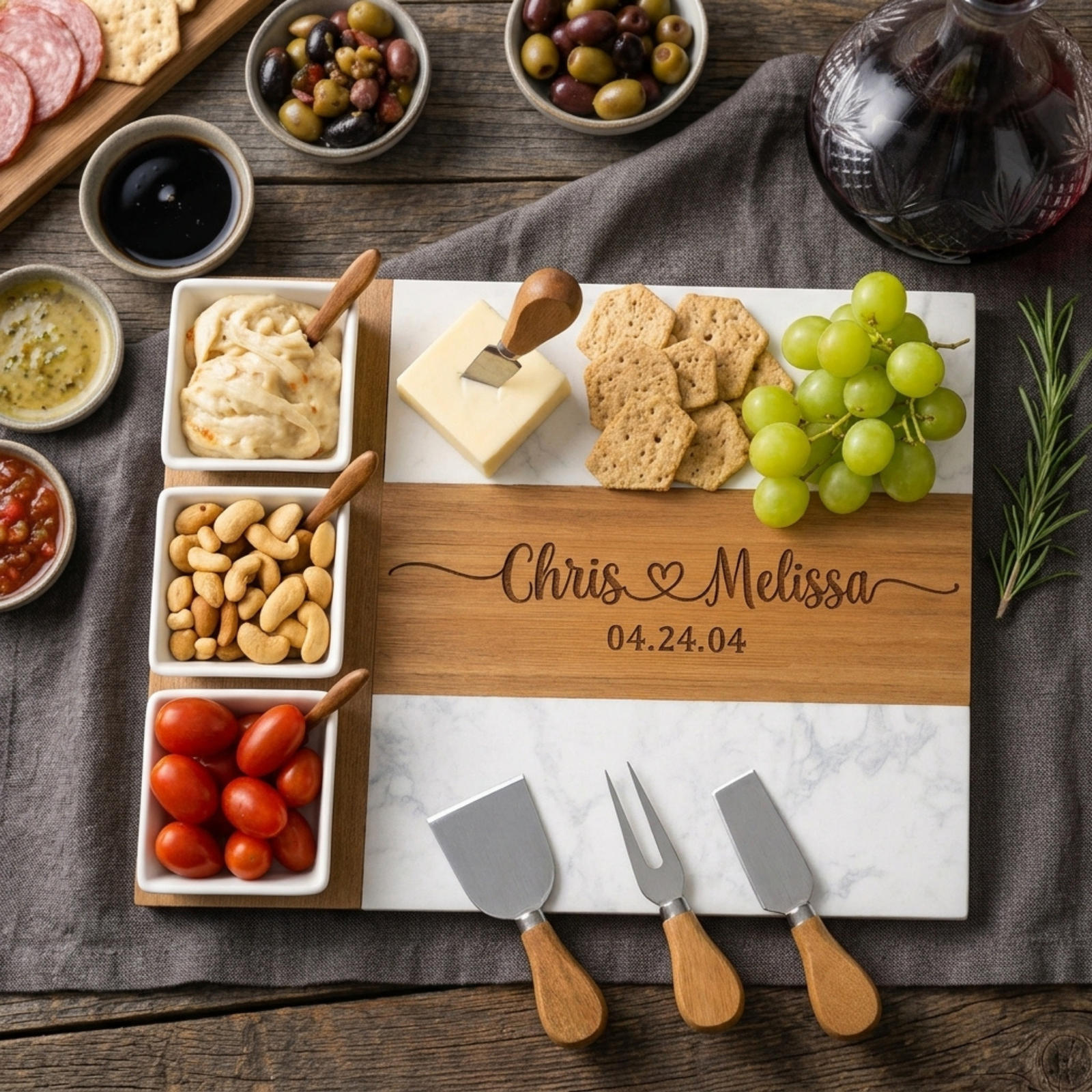 Marble and acacia couples charcuterie board engraved with two names and an anniversary date, set with olives, nuts and cheese.