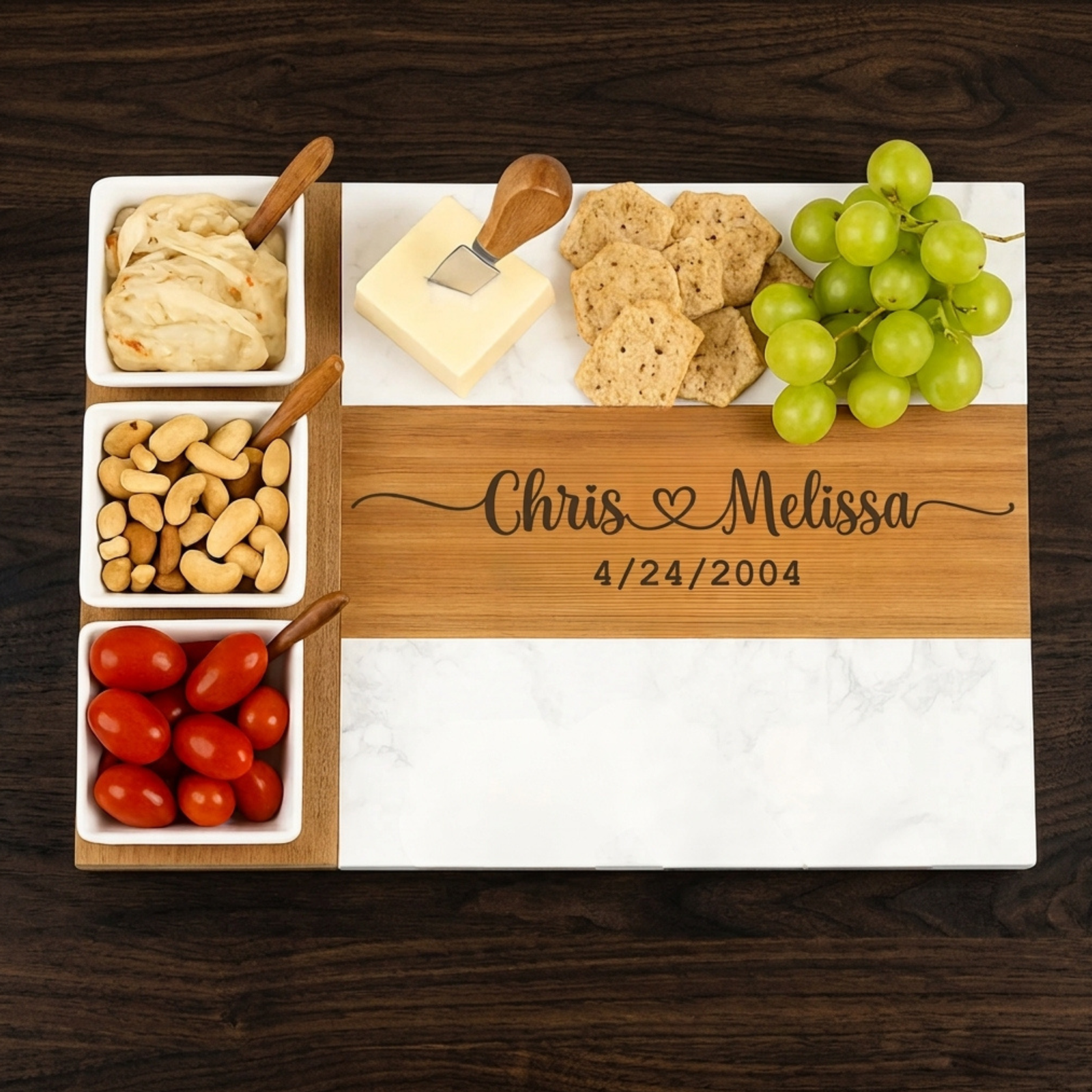Overhead view of a personalized couples charcuterie board with two engraved names, a heart and a date, filled with cheese and fruit.