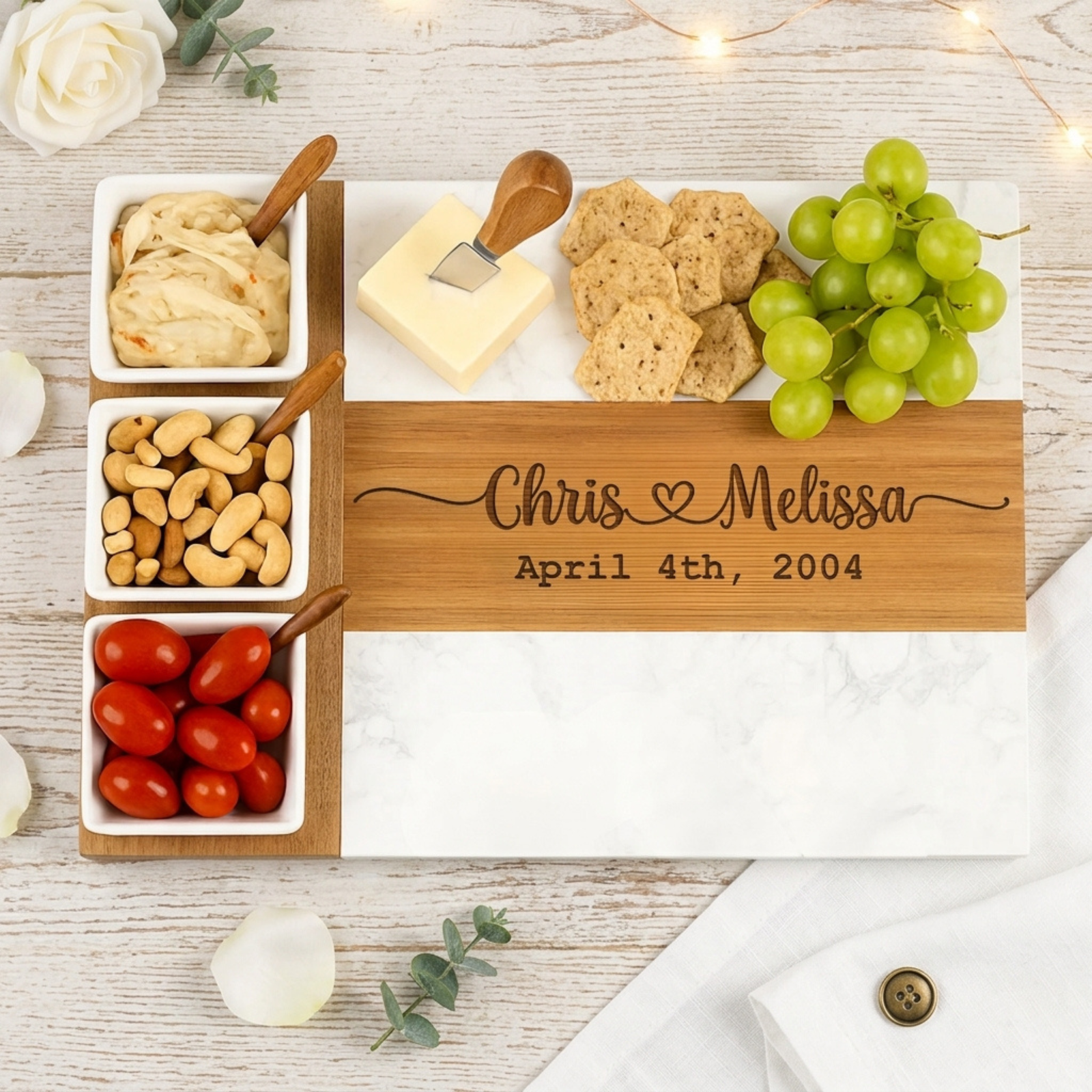 Personalized couples charcuterie board with three ceramic bowls and four cheese tools, engraved with two names and a date.
