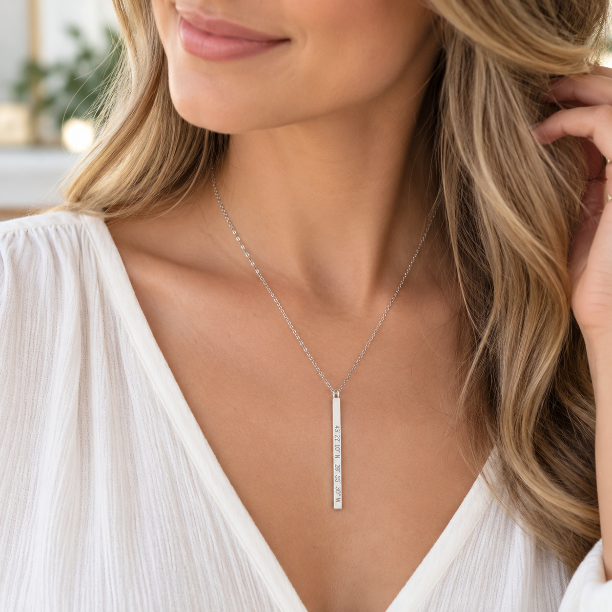 Silver vertical bar necklace with sample coordinate engraving, worn as a pendant on delicate chain.