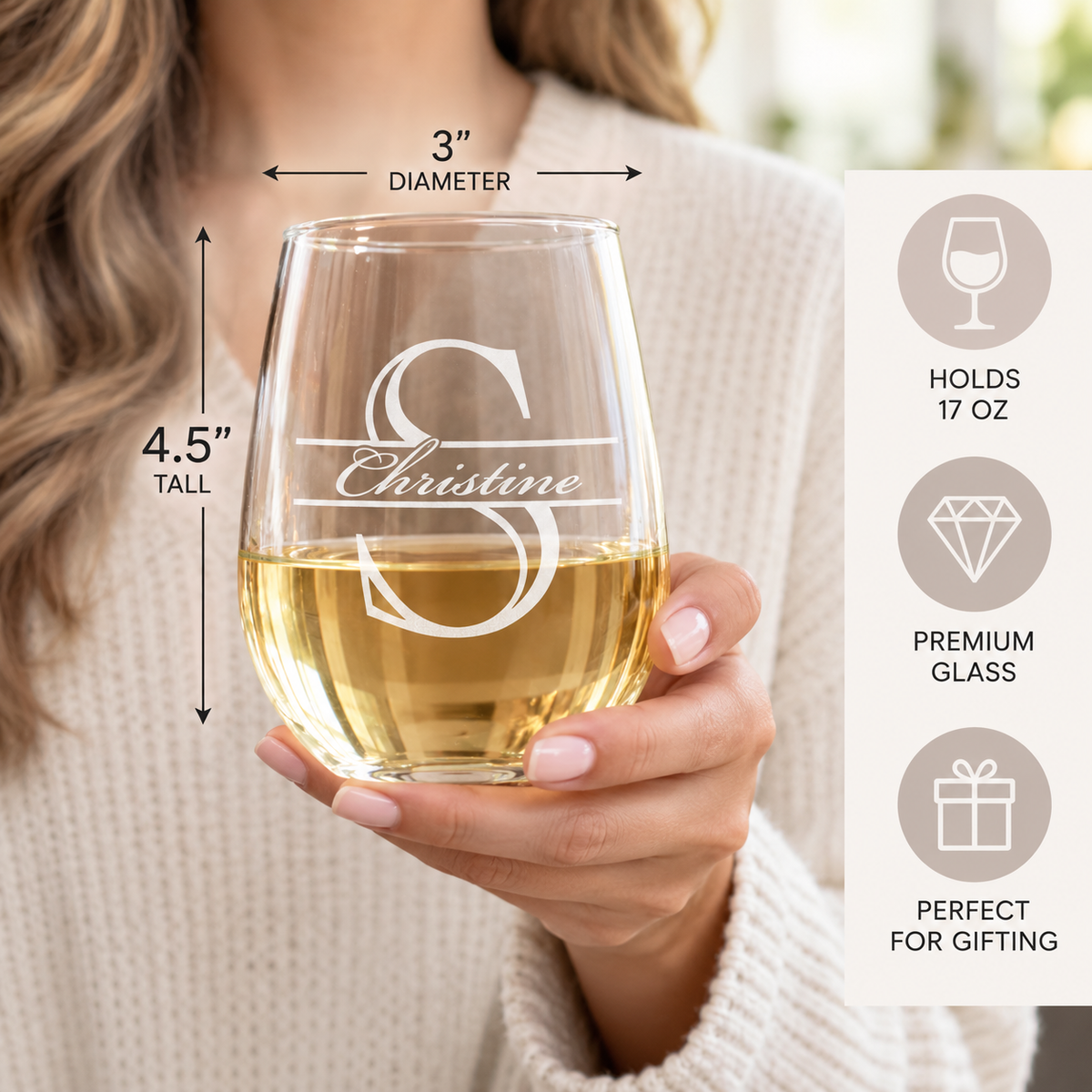 Woman holding a personalized stemless wine glass engraved with S and Christine, with size callouts showing 3 inches in diameter, 4.5 inches tall, and a 17 ounce capacity.