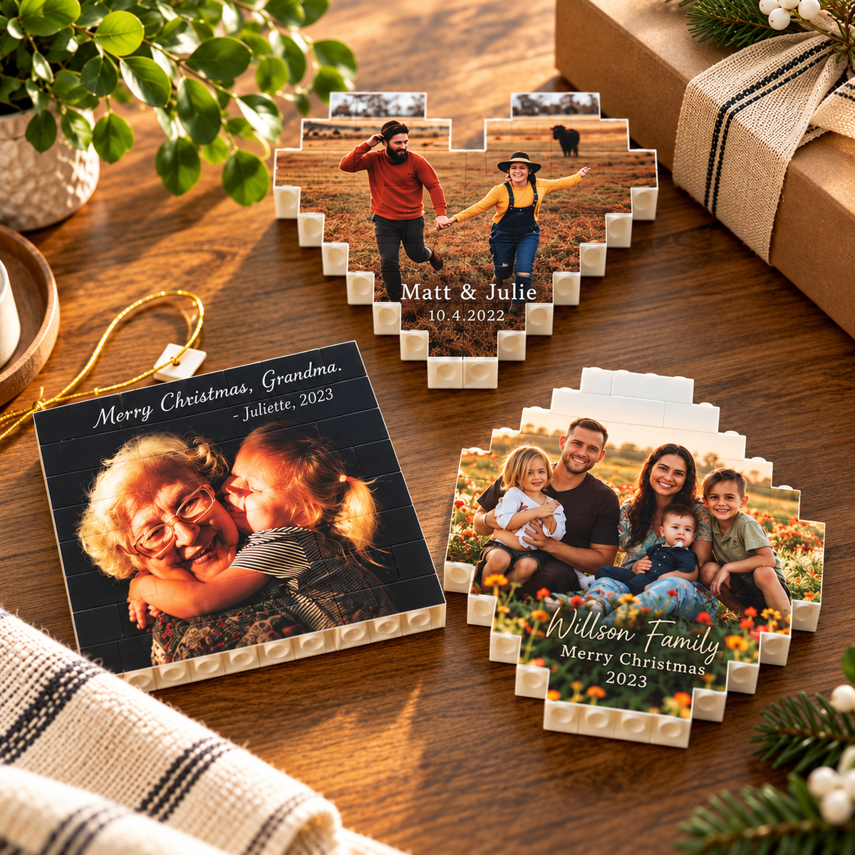 Three finished photo brick keepsakes on a wood table: a rectangular grandmother and grandchild piece, and two heart-shaped family pieces with holiday greetings.