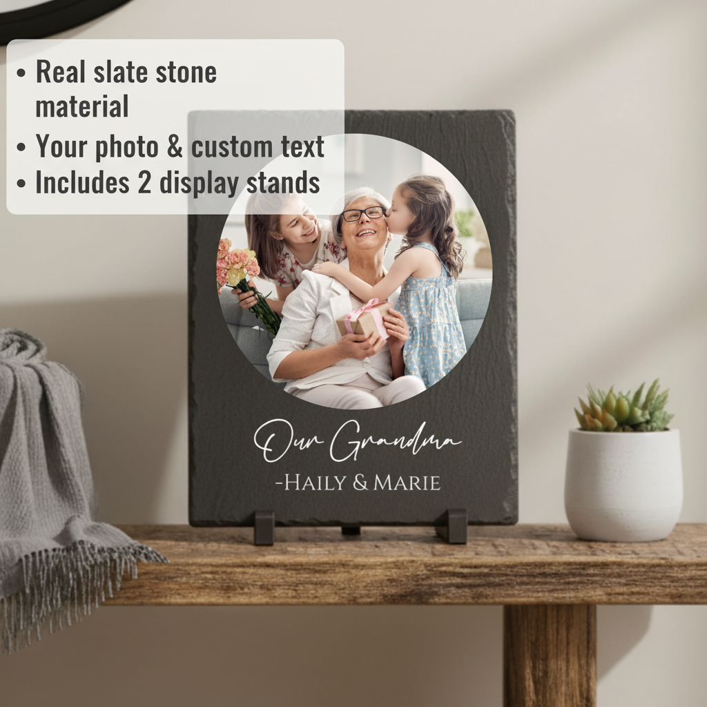 Dark slate plaque with circular photo opening displaying a woman with two girls, engraved with sample text "Our Grandma" and names "HAILY & MARIE", displayed on wooden stand with plastic base feet