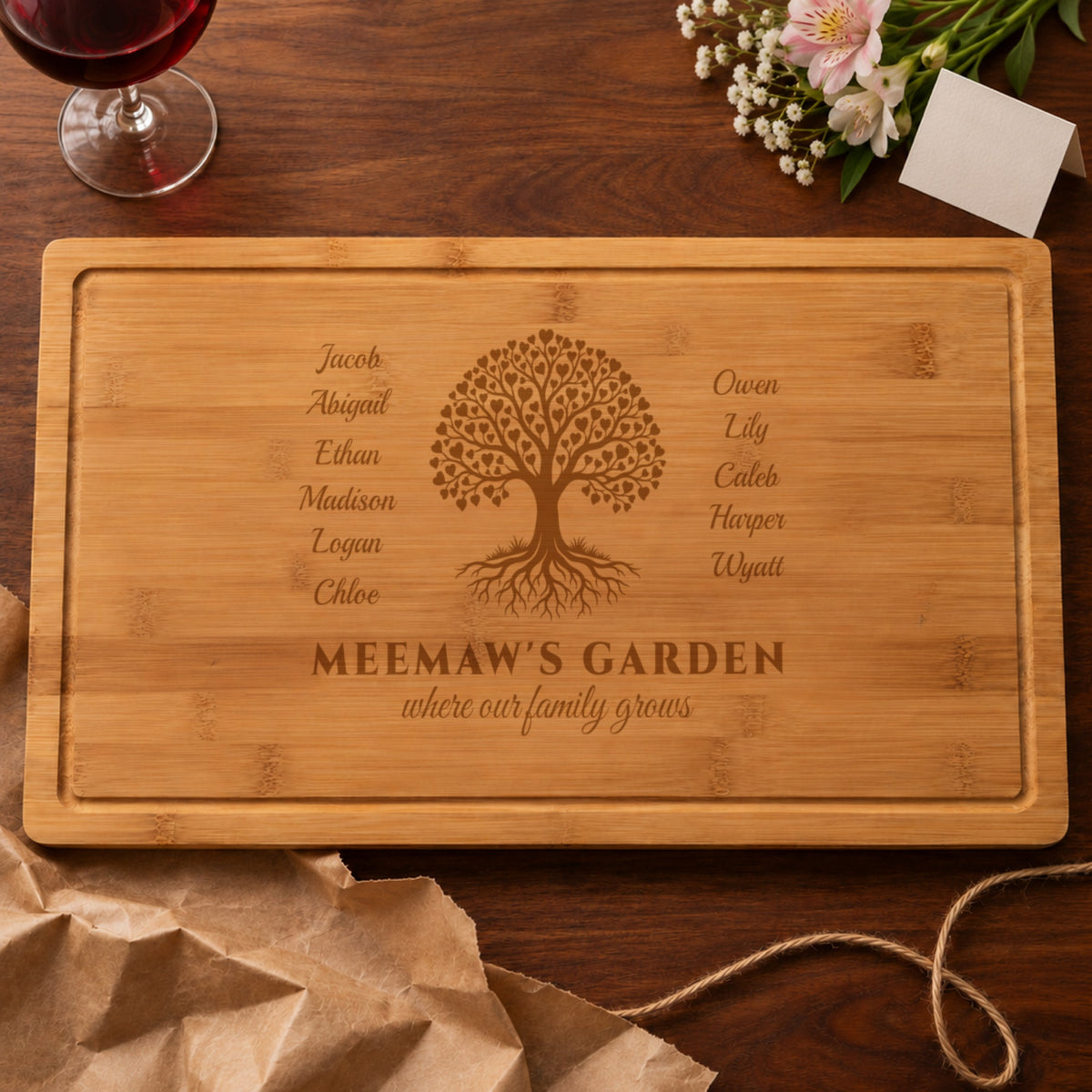 Grandma gift from the grandkids: cutting board engraved MEEMAW'S GARDEN with eleven grandkids' names, unwrapped from kraft paper beside flowers