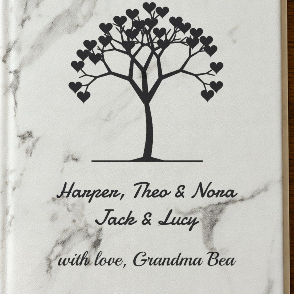 Close-up of the laser engraving on the white marble grandma journal: a tree of hearts above Harper, Theo & Nora, Jack & Lucy and with love, Grandma Bea