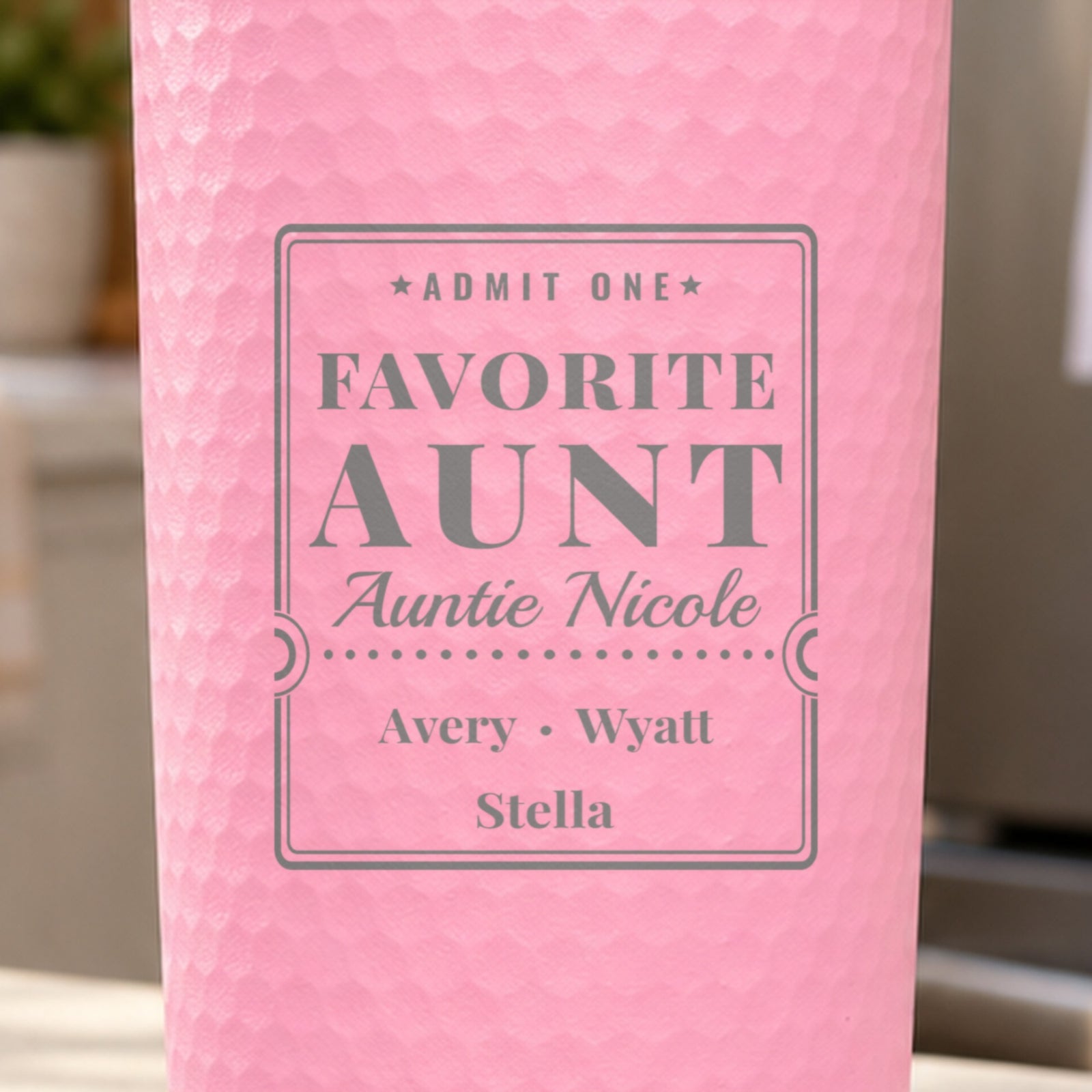 Close-up of the laser engraving on a pink dimpled tumbler: Admit One, Favorite Aunt, Auntie Nicole, Avery, Wyatt and Stella