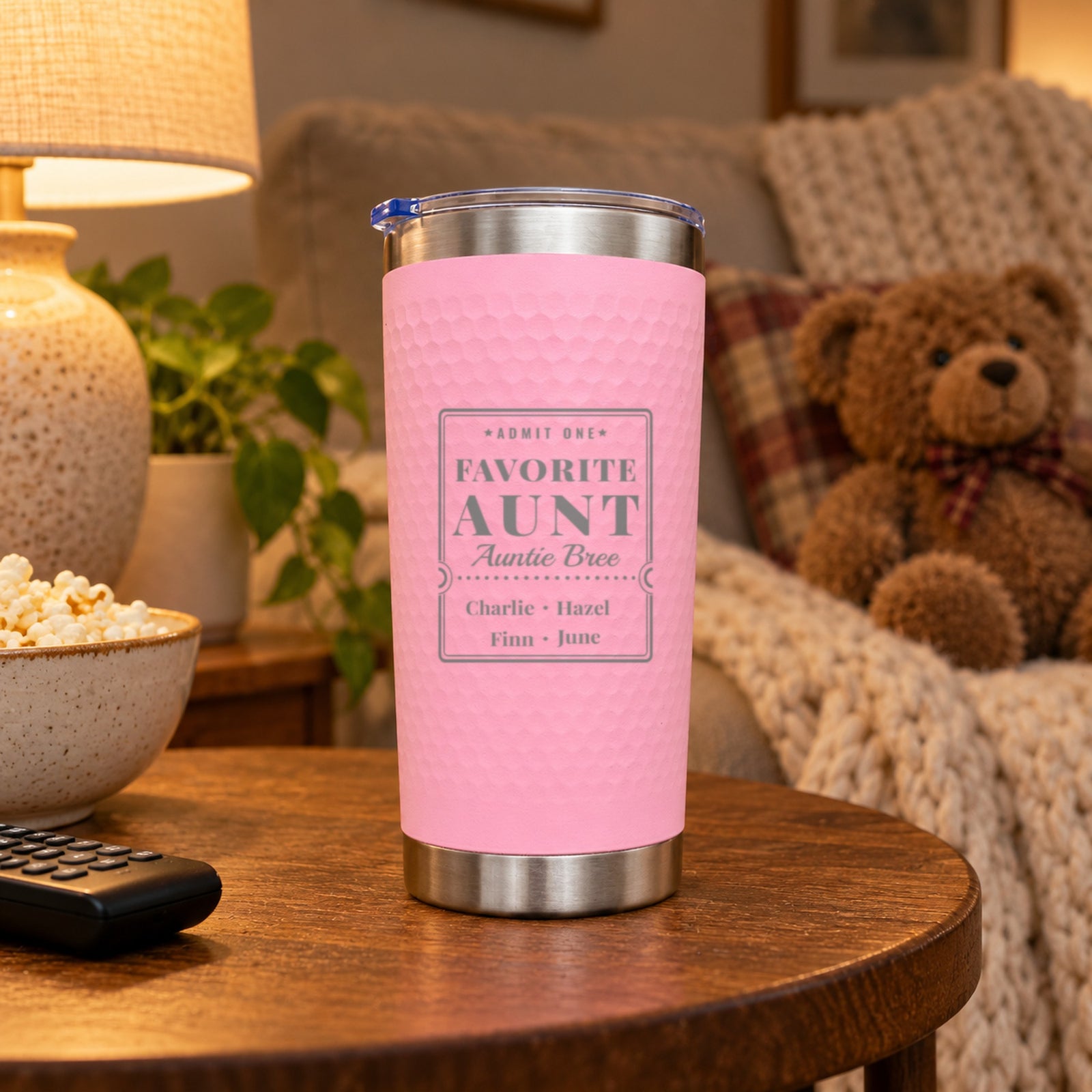 Pink Favorite Aunt tumbler for Auntie Bree with Charlie, Hazel, Finn and June on a side table beside a teddy bear and popcorn