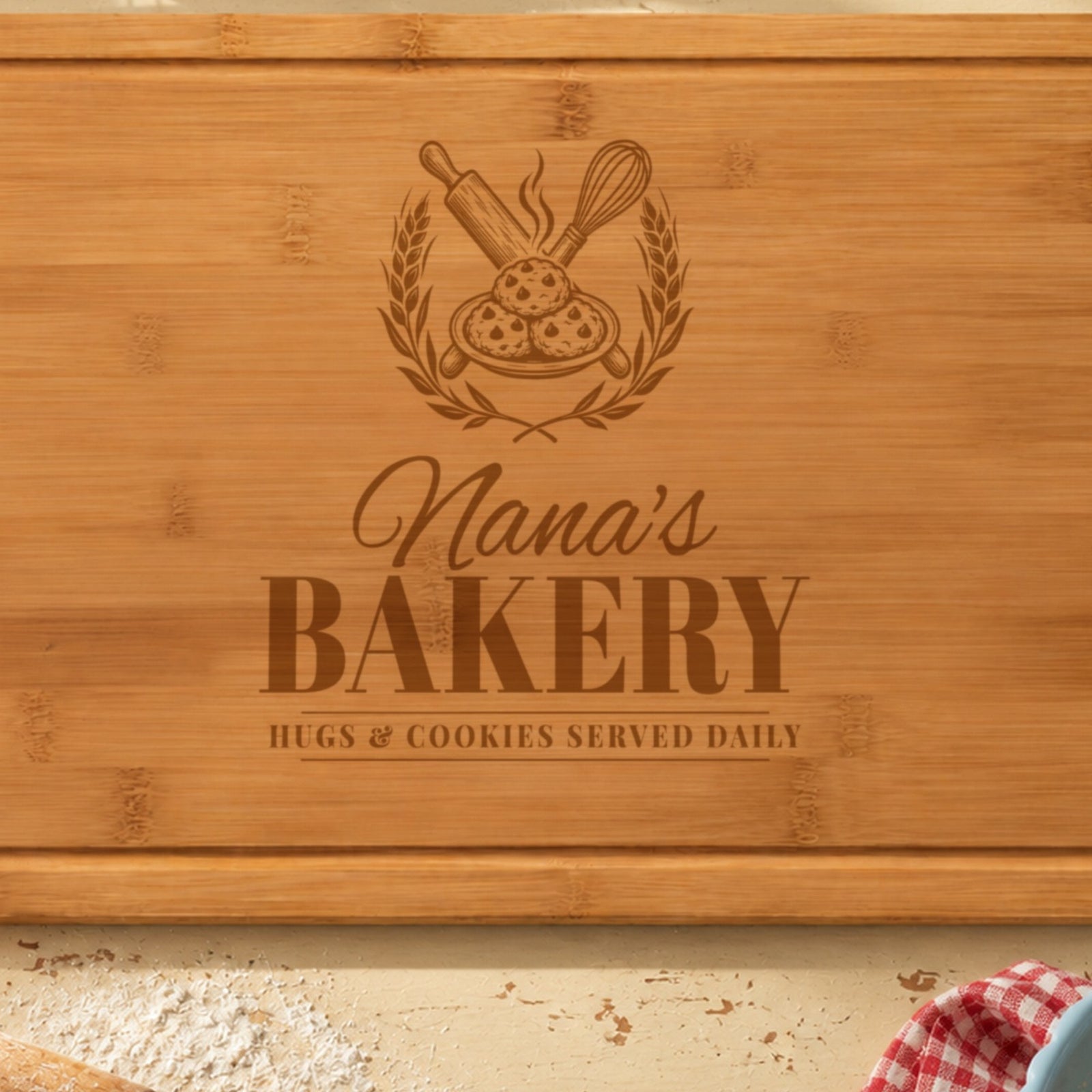 Close-up of the laser engraving on the grandma bakery board: rolling pin, whisk and cookies in a wheat wreath, Nana's in script and BAKERY