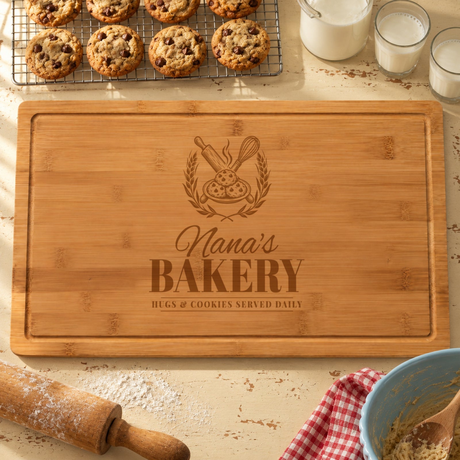 Grandma cutting board engraved like a vintage bakery sign, Nana's BAKERY HUGS & COOKIES SERVED DAILY, with a rolling pin and cookies, beside fresh baked cookies and milk