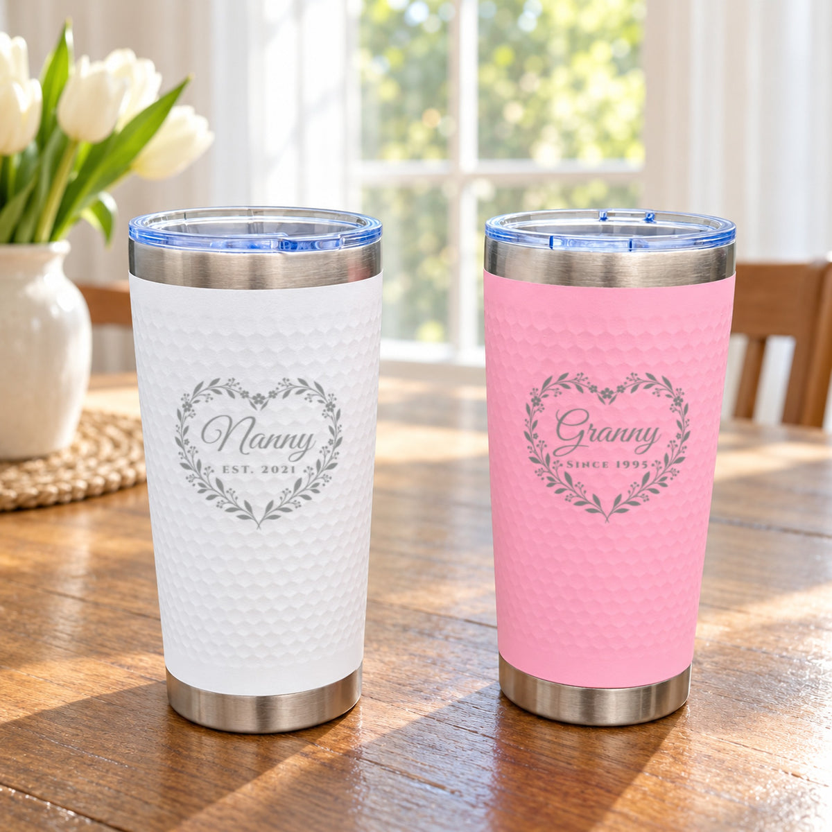 Pink and white heart wreath grandma tumblers engraved for Nanny and Granny, showing both color options side by side on a table