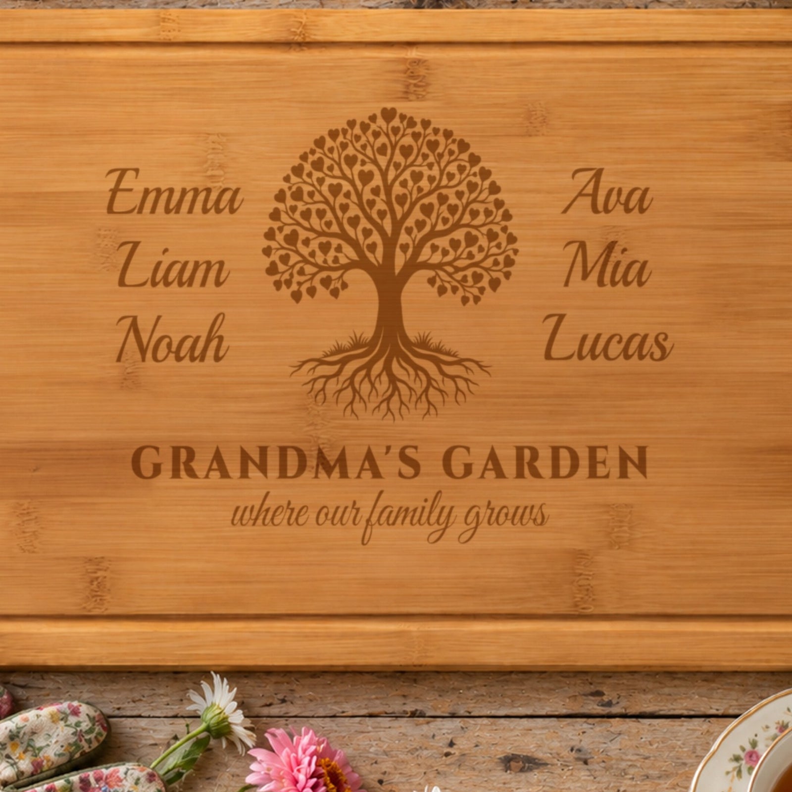 Close-up of the laser engraving on the grandma cutting board: Emma, Liam, Noah, Ava, Mia and Lucas around a family tree of tiny hearts