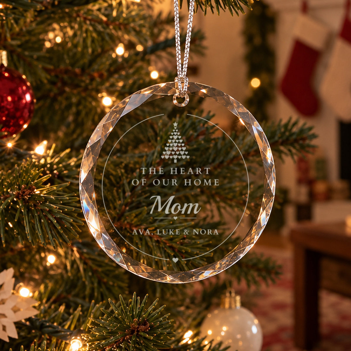 Personalized mom Christmas ornament in clear faceted glass on a family tree, engraved The Heart of Our Home, Mom, and Ava, Luke and Nora under a tree of hearts