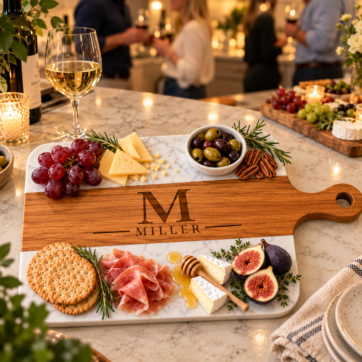 Engraved monogram charcuterie board displayed on a marble counter at an evening gathering with wine and cheese, personalized with initial M and last name Miller.