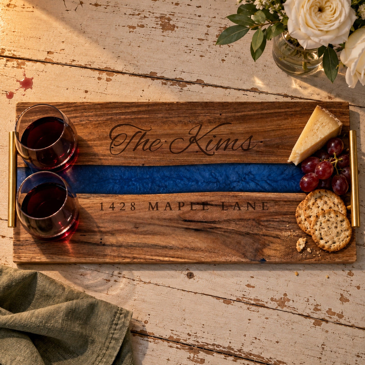 Housewarming gift serving tray engraved The Kims and 1428 Maple Lane, with two glasses of red wine, cheese, grapes and crackers on a farmhouse table