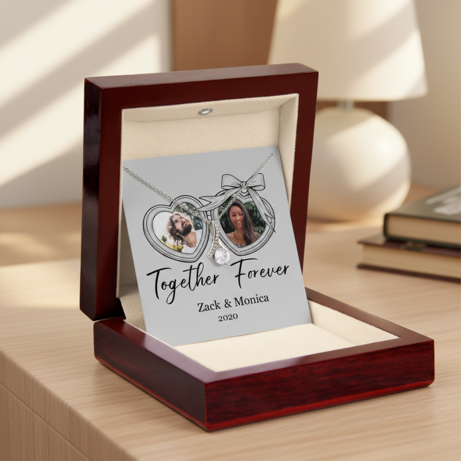 Double heart-shaped locket necklace pendant with two sample photos displayed on personalized card reading "Together Forever" with sample names "Zack & Monica" and year "2020" in burgundy gift box.