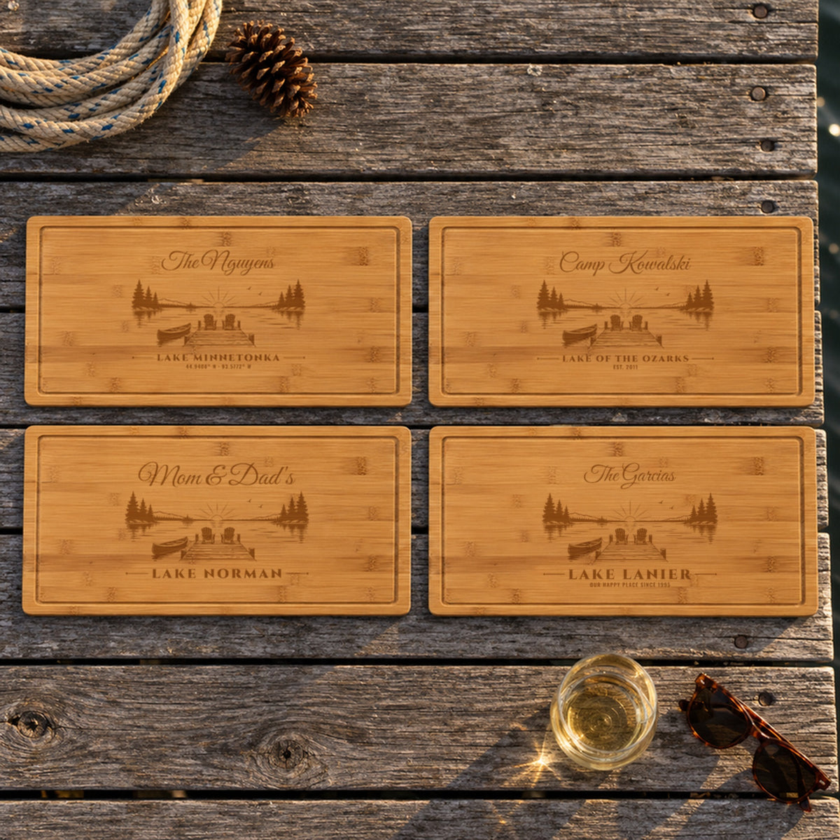 Four engraved lake house sign boards on a dock: The Nguyens Lake Minnetonka, Camp Kowalski Lake of the Ozarks, Mom & Dad's Lake Norman, The Garcias Lake Lanier
