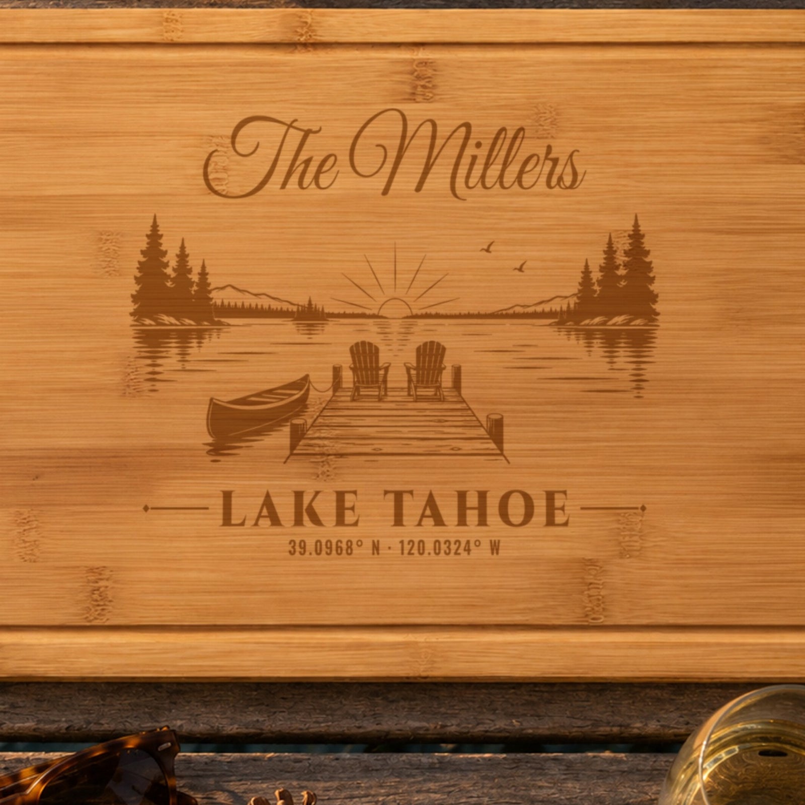Close-up of the laser engraving on the lake house cutting board: The Millers in script, a dock with two Adirondack chairs and a canoe, and Lake Tahoe