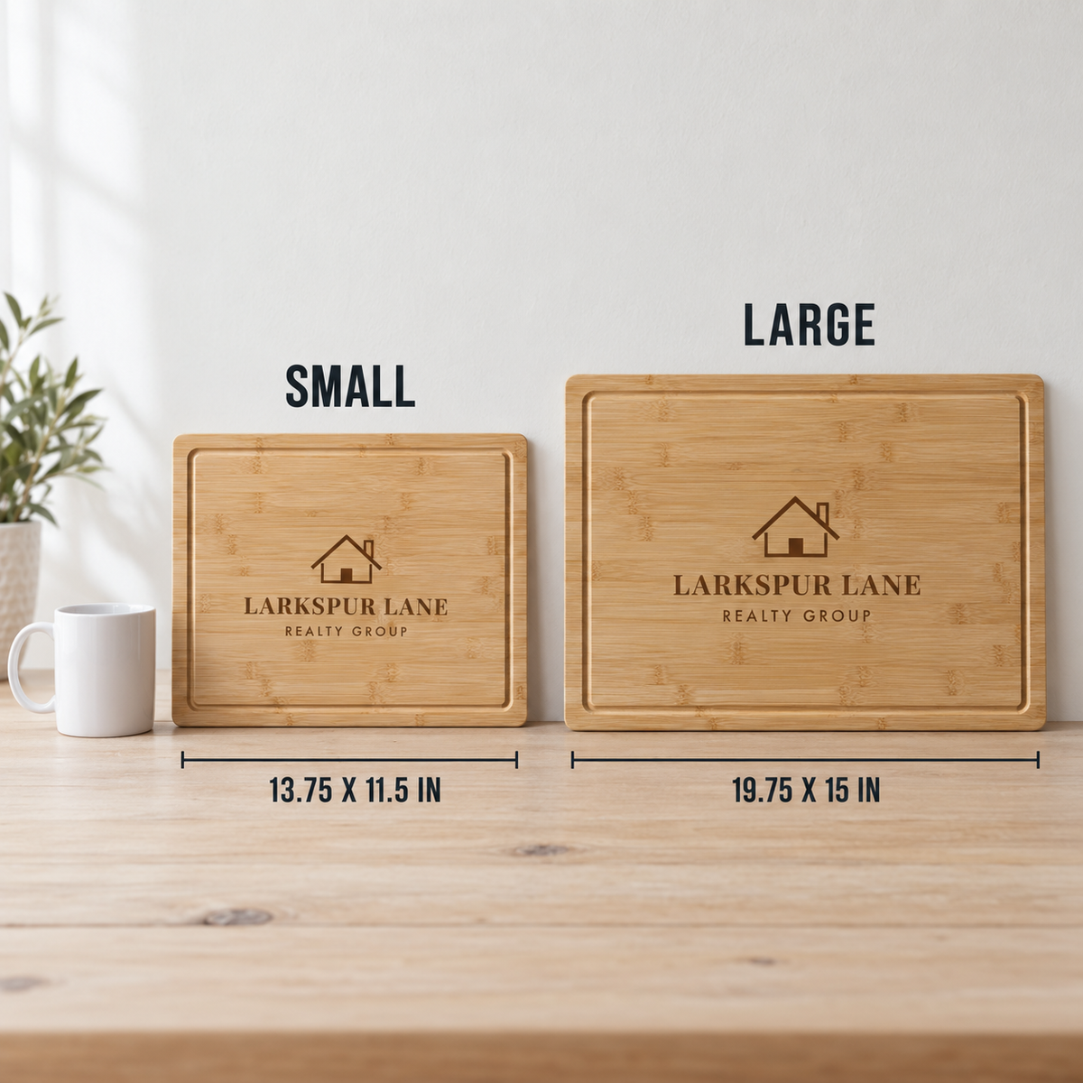 Two personalized bamboo cutting boards shown on a wooden table against a white wall, labeled SMALL and LARGE with dimensions underneath. A white mug and a small plant are visible as props.